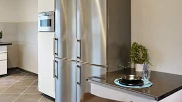 Una cocina moderna con electrodomésticos de acero inoxidable, horno empotrado y una pequeña isla con un tazón y un vaso.