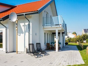 A modern house with a balcony, outdoor seating, and a satellite dish.