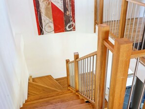 A wooden staircase with a metal railing, leading to a room with a white wall and a painting. - Holiday Home in Falkenberg (Glommen)
