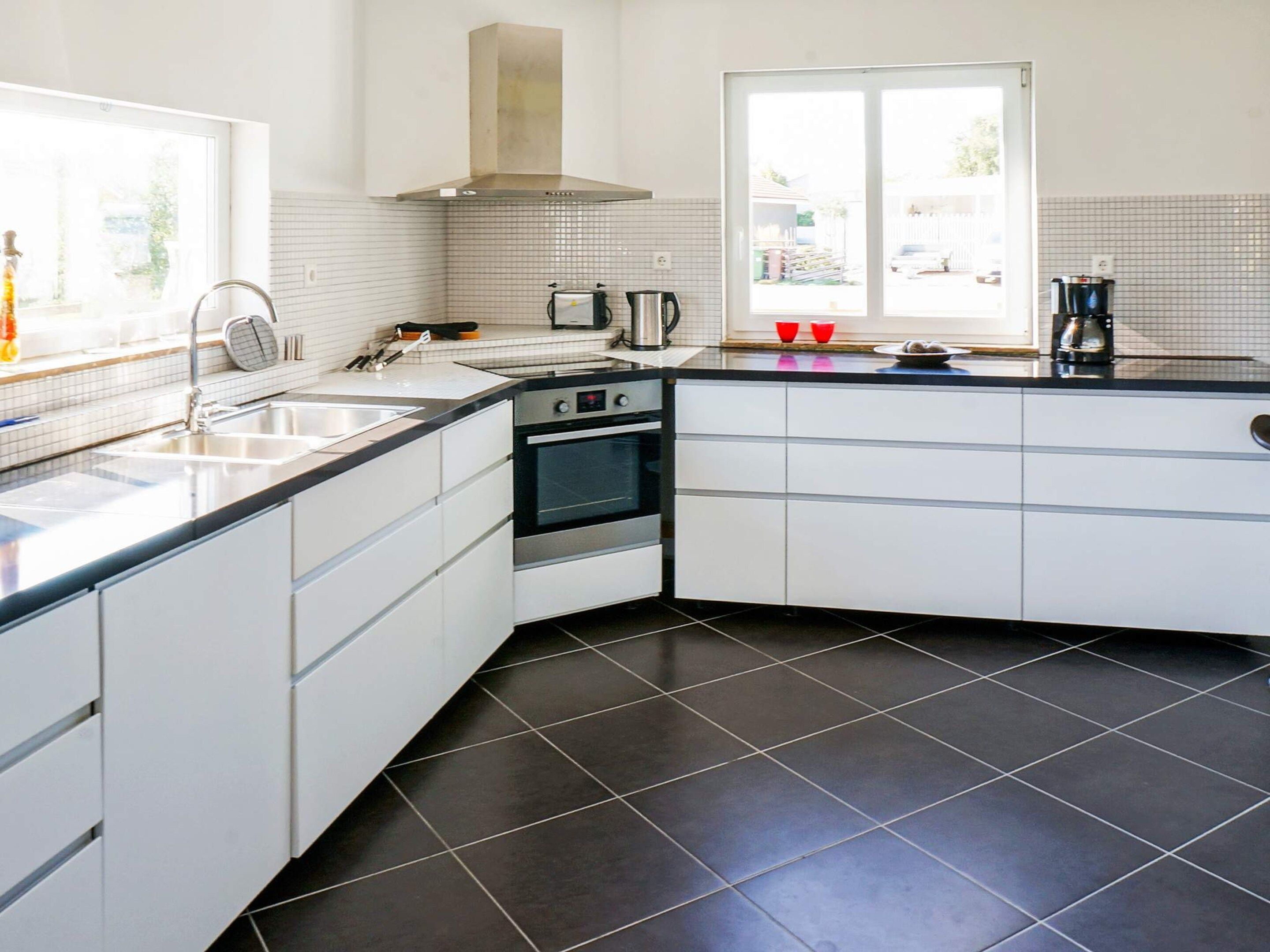 Una cocina moderna con armarios blancos, encimera negra, estufa y ventana.