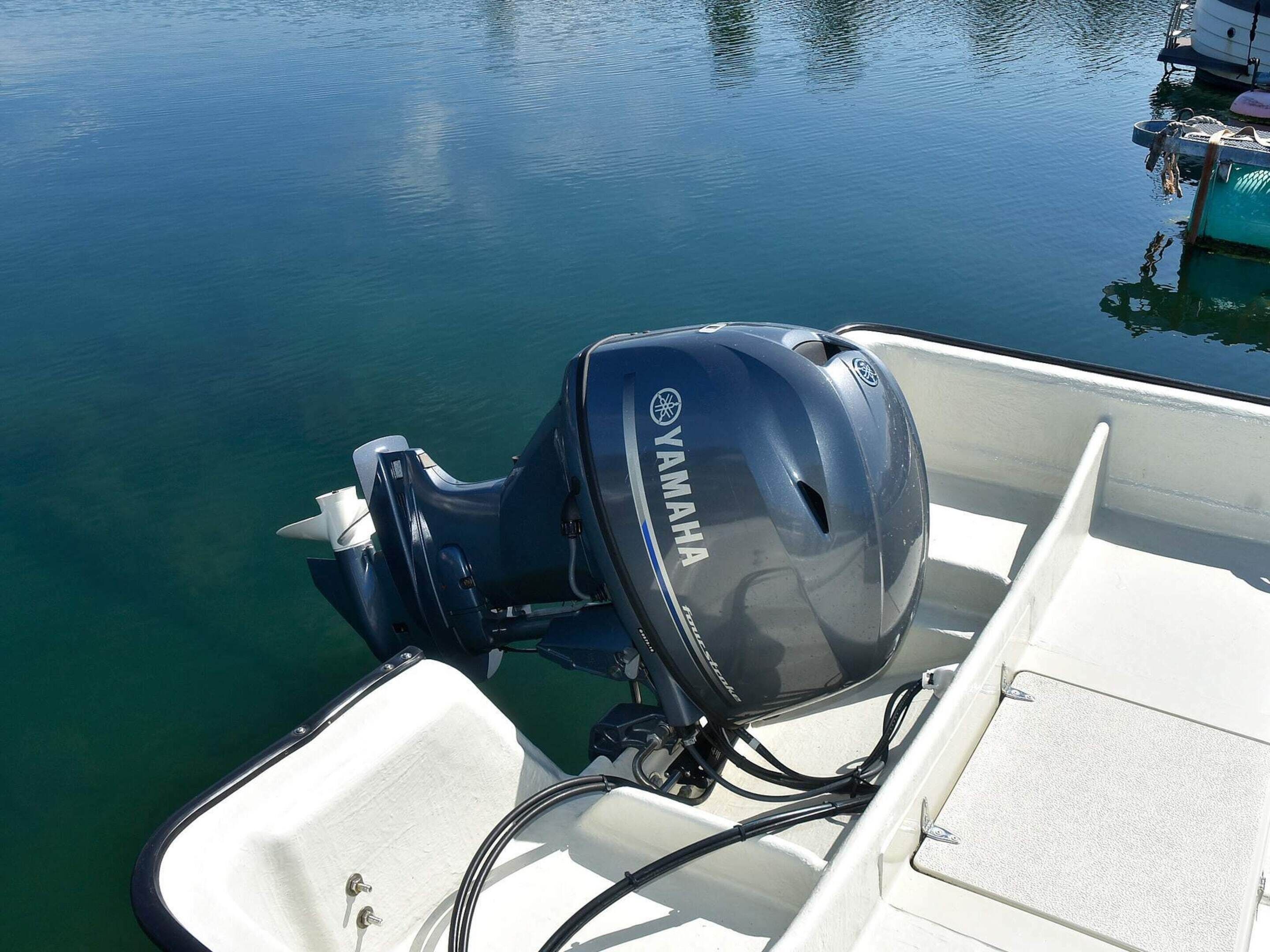 Een boot met een Yamaha buitenboordmotor, een witte binnenkant en rustig water.