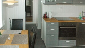 Een kleine keuken met een magnetron, oven en een eethoekje met een tafel en stoelen.