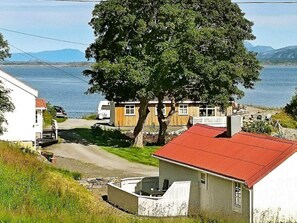 Ett bostadsområde vid kusten med hus, ett stort träd och utsikt över havet.