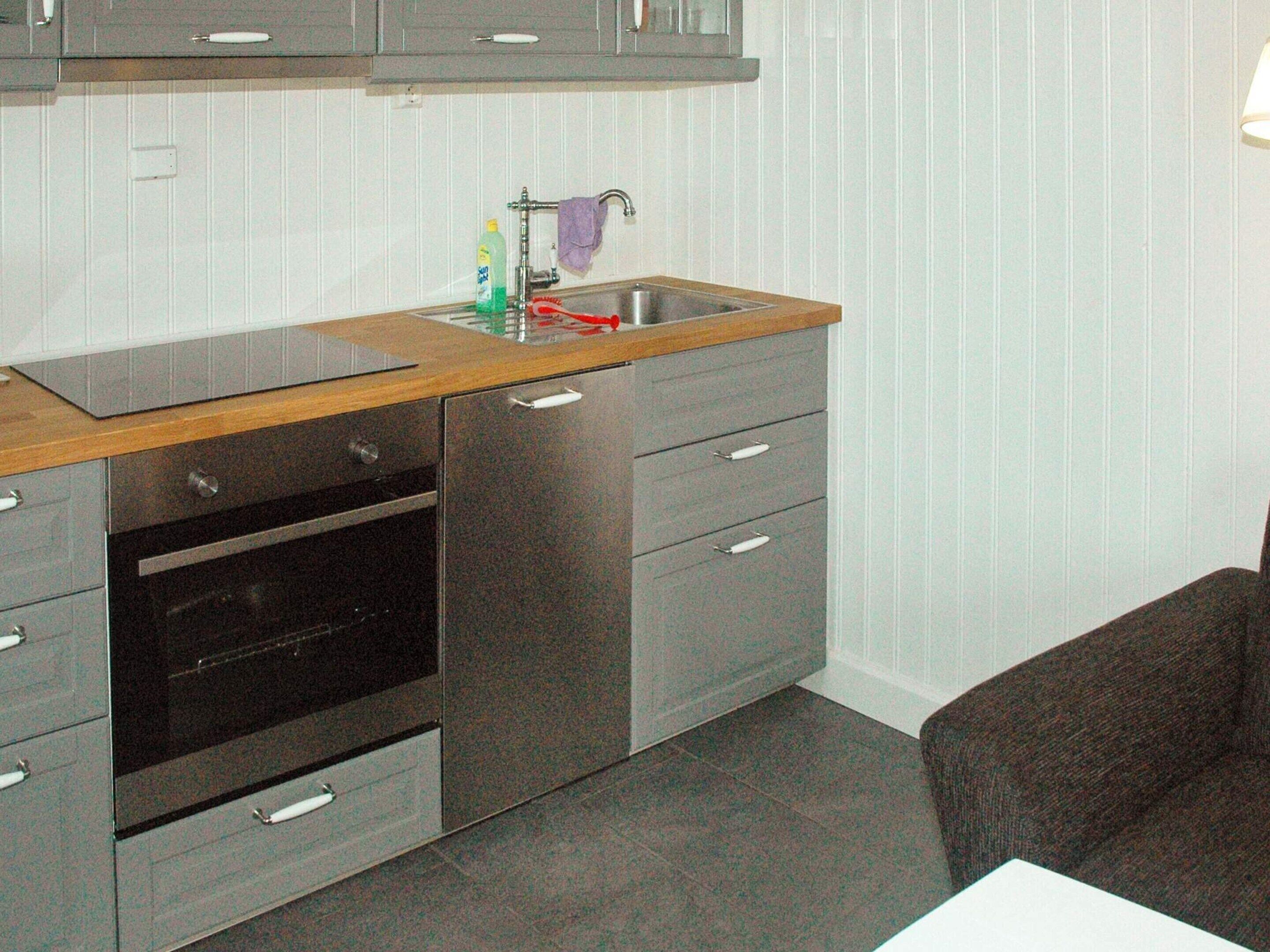 Eine kleine Küche mit einer Holz Arbeitsplatte, Edelstahlgeräten und einem Schubladenschrank.