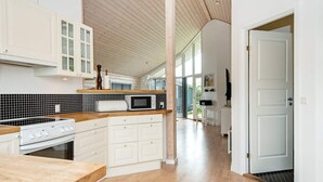 A modern kitchen with white cabinetry, a wooden countertop, a built-in microwave, and a stove. - 6 Person Holiday Home in Juelsminde-by Traum (Juelsminde)
