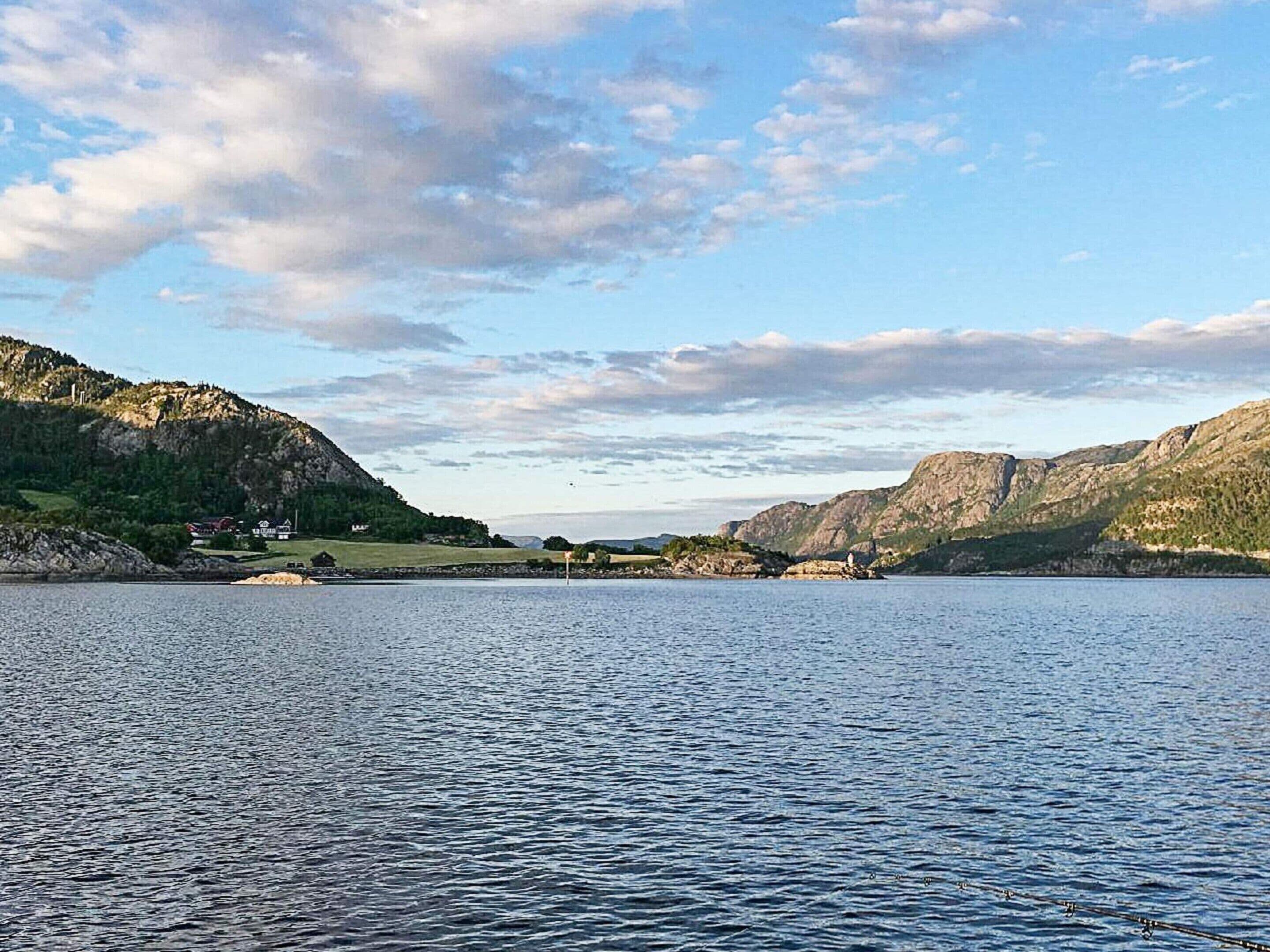 A lake with mountains in the background and a small building on the shore.