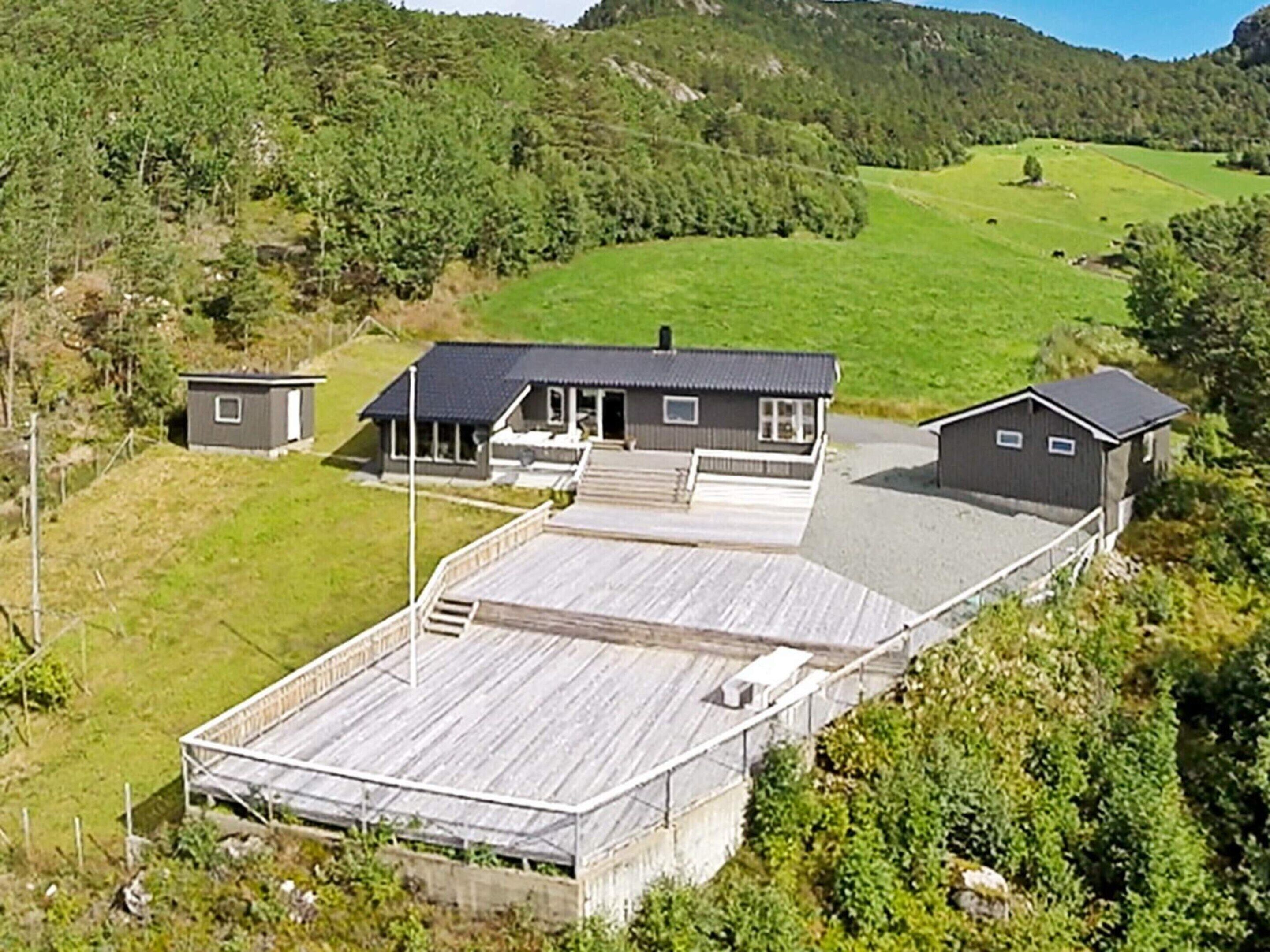 Une grande maison avec une terrasse en bois et un petit quai pour bateaux.