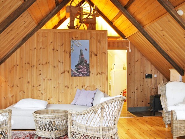 A cozy wooden interior with a high ceiling, a sofa, two wicker chairs, and a refrigerator in the background. - 5 Person Holiday Home in Lonevag (Osteroy)