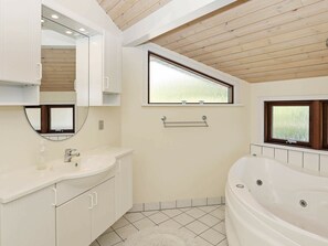 A modern bathroom with a freestanding bathtub, a vanity with a mirror, and a window with blinds.