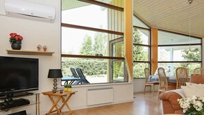 A modern living room with a flat-screen TV, a wooden coffee table, and a sofa. Large windows offer a view of the outdoors. - Luxurious Holiday Home Near Hals With Whirlpool (Hals)