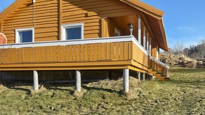 Une maison en bois avec un balcon, une petite fenêtre et un lampadaire.