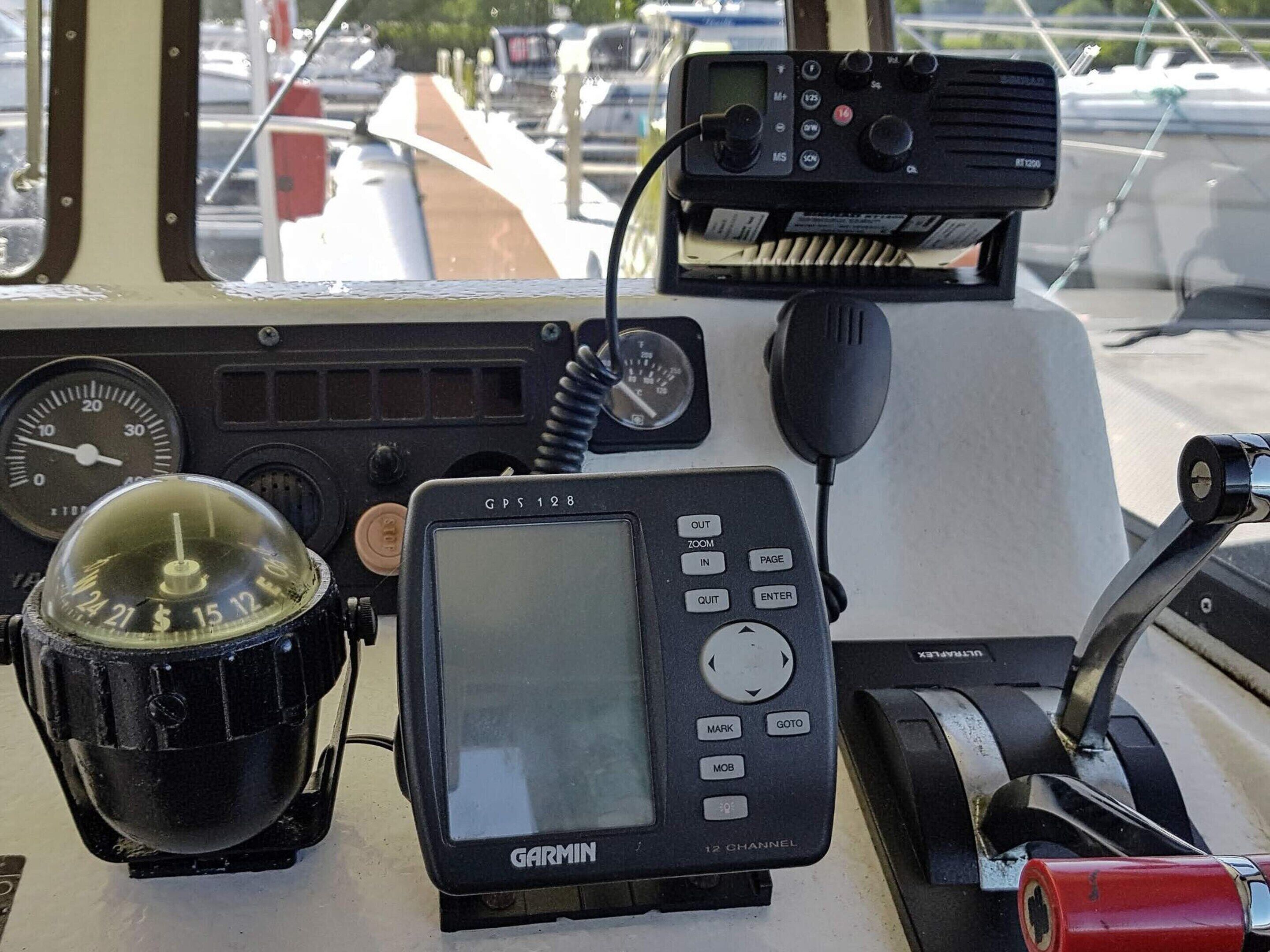 A Garmin GPS device on a boat's control panel, a compass, and a speedometer.