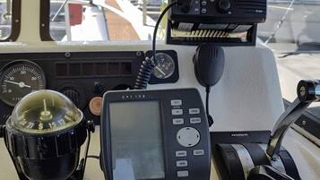 A Garmin GPS device on a boat's control panel, a compass, and a speedometer.