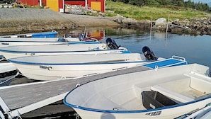 Une rangée de petits bateaux à moteur blancs était amarrée à un quai, avec un bâtiment rouge en arrière-plan.