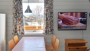 Un espace repas comprenant une table, des chaises, un téléviseur et une vue sur l’extérieur.