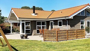 A two-story house with a tiled roof, a fenced backyard, and a wooden deck. - 8 Person Holiday Home in Sjolund-by Traum (Sjølund)