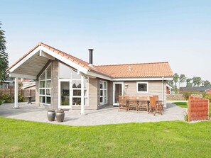 A two-story house with a covered patio, a chimney, and a garden. - 8 Person Holiday Home in Sjolund-by Traum (Sjølund)