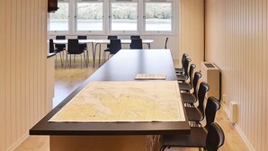 Una sala conferenze con un grande tavolo, sedie e una mappa.