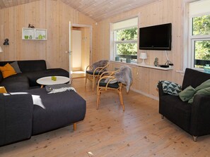 Un salon moderne avec un canapé, des fauteuils, un téléviseur et une petite table.