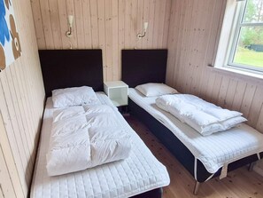Ein Zimmer mit zwei Betten, einem kleinen Tisch und einem Fenster.