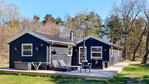A two-story cabin with a covered porch and outdoor seating area. - Attractive Holiday Home with Whirlpool near Hadsund (Hadsund)