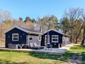 Eine zweistöckige Holzhütte mit überdachter Veranda und Sitzgelegenheit im Freien.