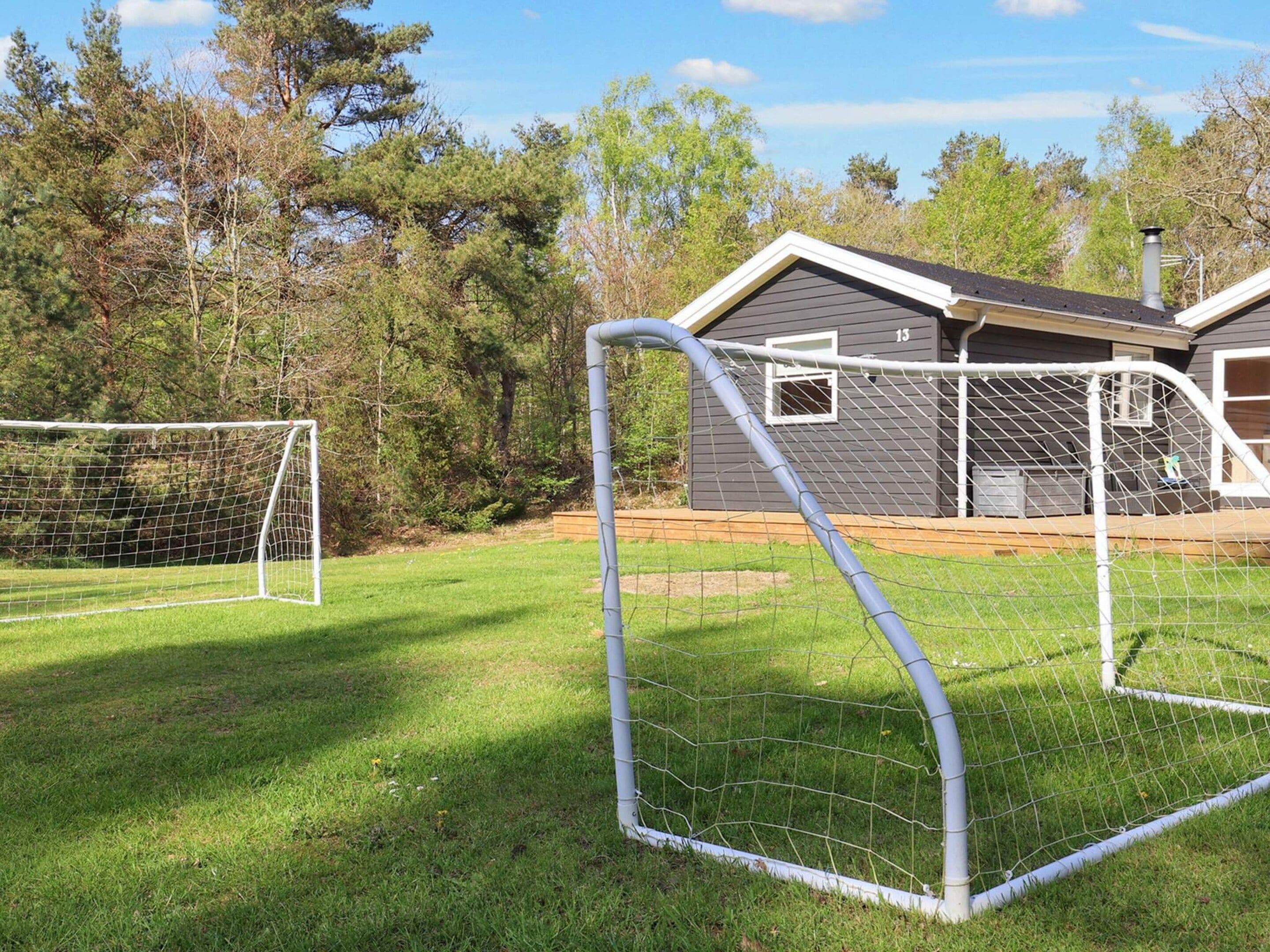 A fenced soccer goal area with a house in the background.