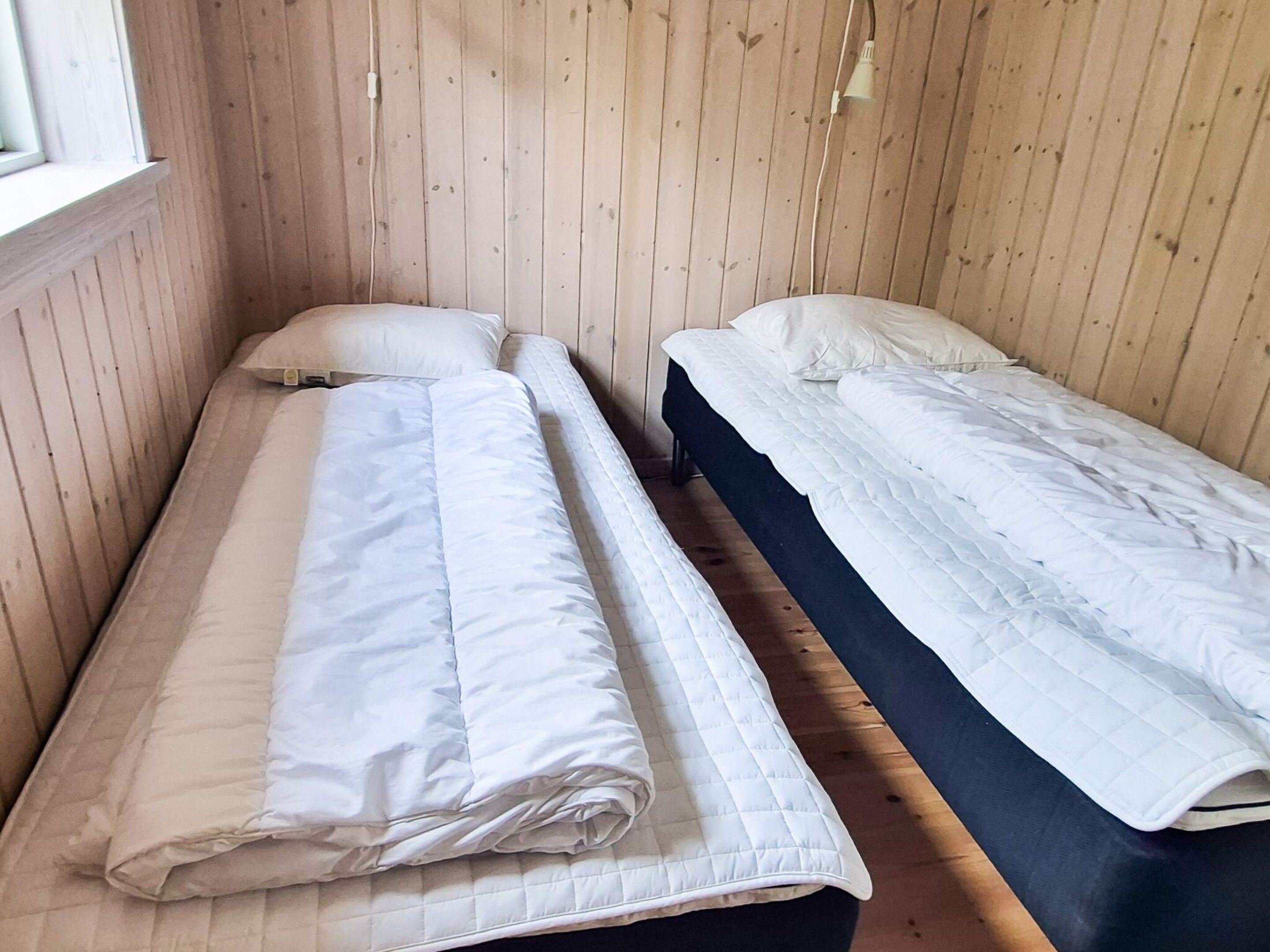 A room with two single beds, wooden walls, and a window.