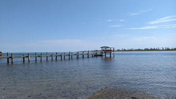 A wooden pier extending into calm water with a small boat docked at the end.