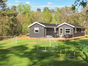 Ein zweistöckiges Haus mit Terrasse und einem umzäunten Garten.