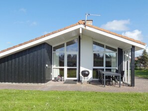 A modern house with a sloped roof, large windows, and a patio area with outdoor furniture. - 10 Person Holiday Home in Lokken-by Traum (Lokken)