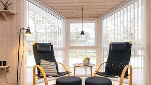 A cozy room with two black cushioned chairs, a small round table with a plant, and a floor lamp.