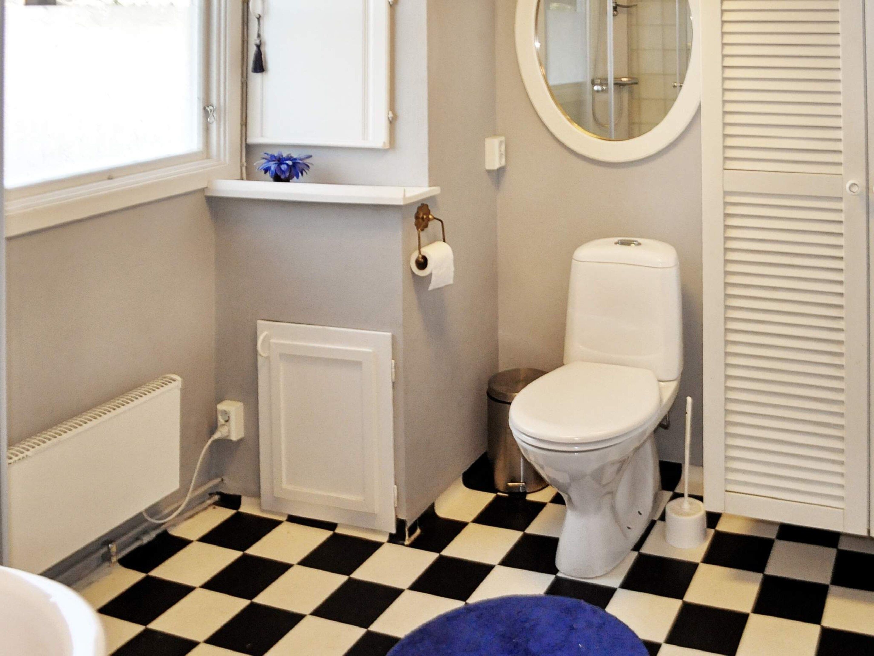 A bathroom with a toilet, a radiator, a sink, and a mirror.