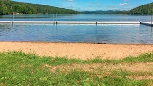 Een meer met een zandstrand en een grasveld op de voorgrond.