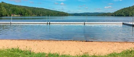 A lake with a sandy shore and grassy area in the foreground.