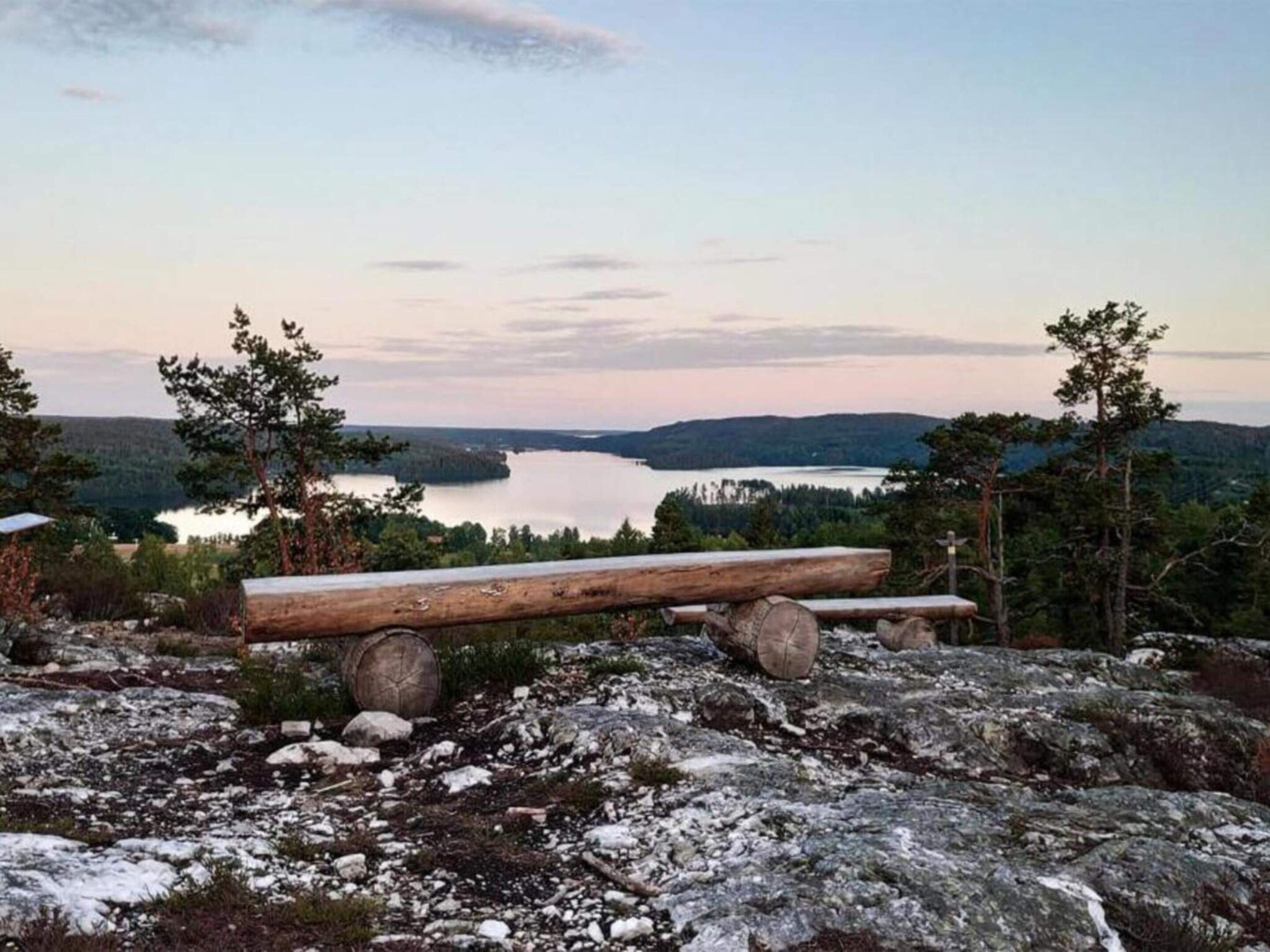 A bench overlooking a lake with surrounding trees and rocky terrain.