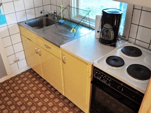 Une cuisine équipée d’un évier à deux bacs, d’une machine à café et d’une cuisinière.