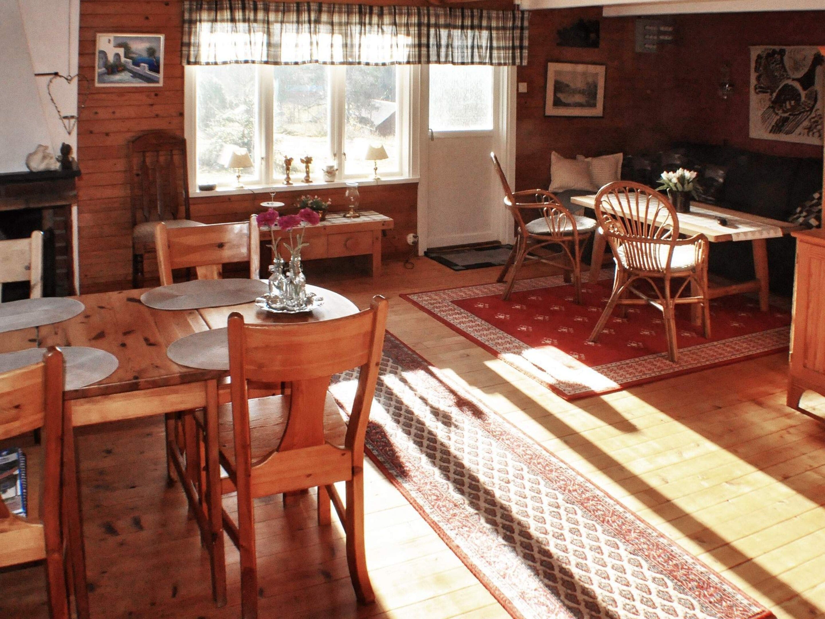 Un comedor acogedor con mobiliario de madera, una mesa con sillas y un ventanal con cortinas.