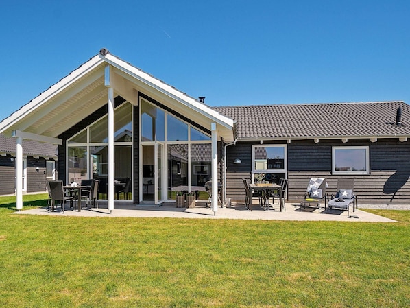 Une maison moderne dotée d’un patio couvert, d’un coin repas et d’un garage.