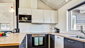 A modern kitchen with white cabinets, a built-in oven, and a dishwasher. - Holiday Home in Kappeln (Kappeln)