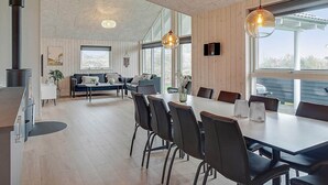 A modern living room with a large dining table, comfortable seating, and a fireplace. - Holiday Home in Kappeln (Kappeln)