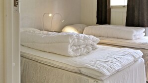 Une chambre d’hôtel avec deux lits, une fenêtre avec des rideaux et un luminaire fixé au mur.