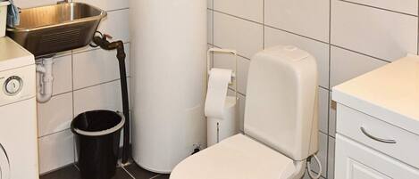 A bathroom with a toilet, a sink, a water heater, and a trash bin.