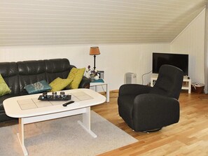 A living room with a black leather sofa, a white coffee table, a black armchair, a TV, and a lamp. - Holiday Home in Leirvik I Sogn (Hyllestad)