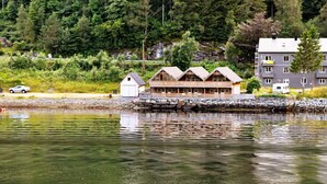 Un chalet avec des fondations en pierre, des cabanes en bois et un grand bâtiment doté de nombreuses fenêtres.