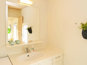 A bathroom with a white sink, a mirror, and a potted plant on the wall. - Luxurious Holiday Home in Millinge With Roofed Terrace (Millinge)