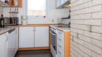 A compact kitchen with white cabinets, a built-in oven, and a window above the sink.