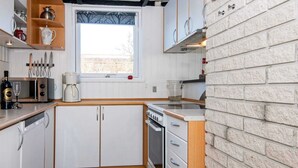 A compact kitchen with white cabinets, a built-in oven, a microwave, and a window with a view of the outdoors. - Fantastic Holiday Home with Bay View near Knebel (Knebel)