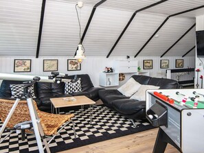 Un salon chaleureux avec un canapé, une table basse, un sol à carreaux et une table de baby-foot.