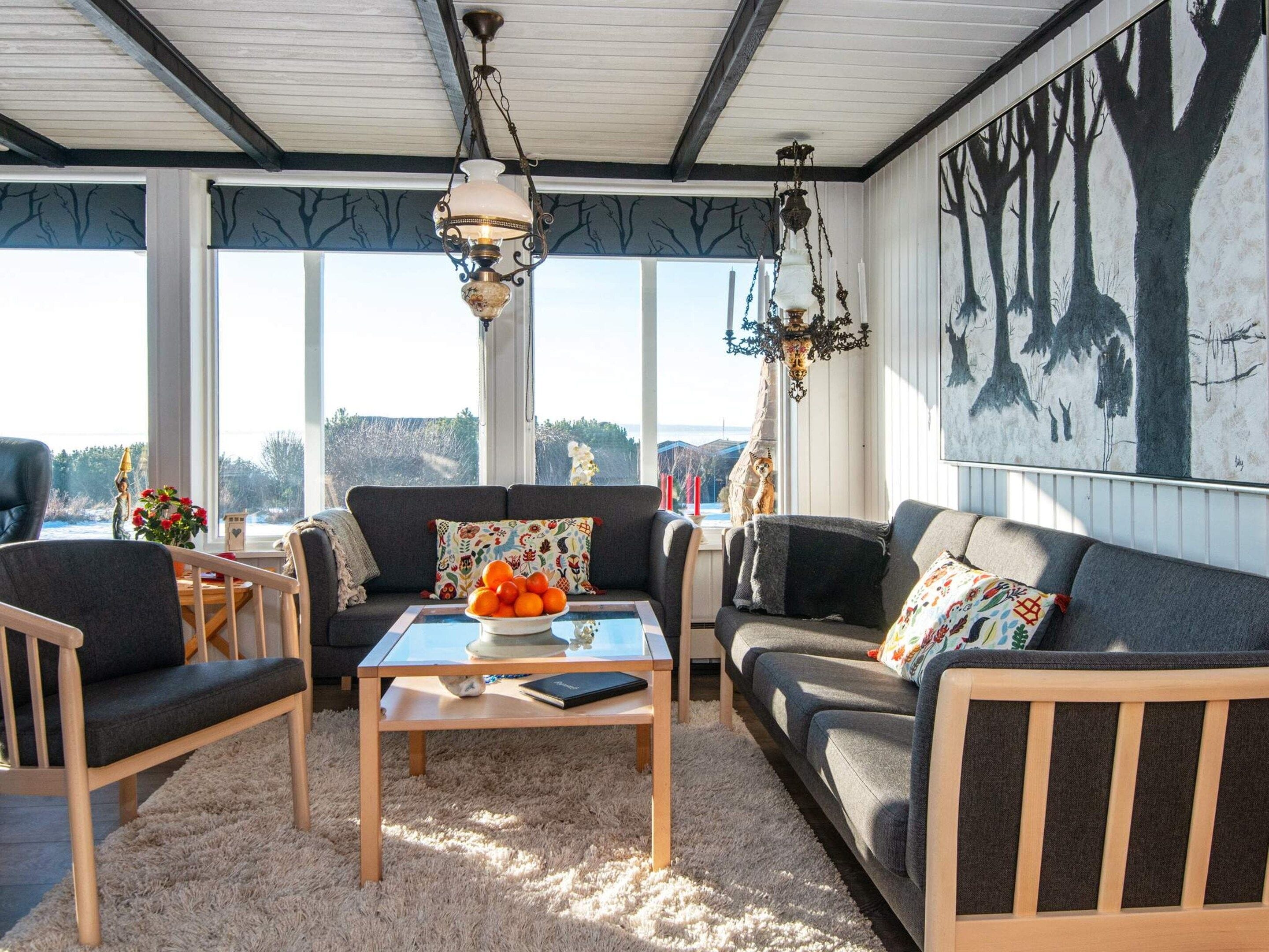 A cozy living room with a sofa, chairs, a coffee table, and a large window with a view.